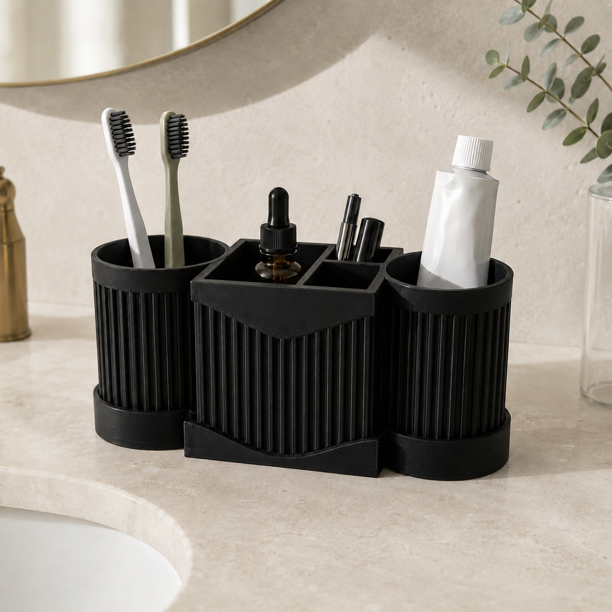 A black three-compartment toothbrush holder set on a bathroom counter, holding two toothbrushes, a dropper bottle, pens, and a tube of toothpaste.