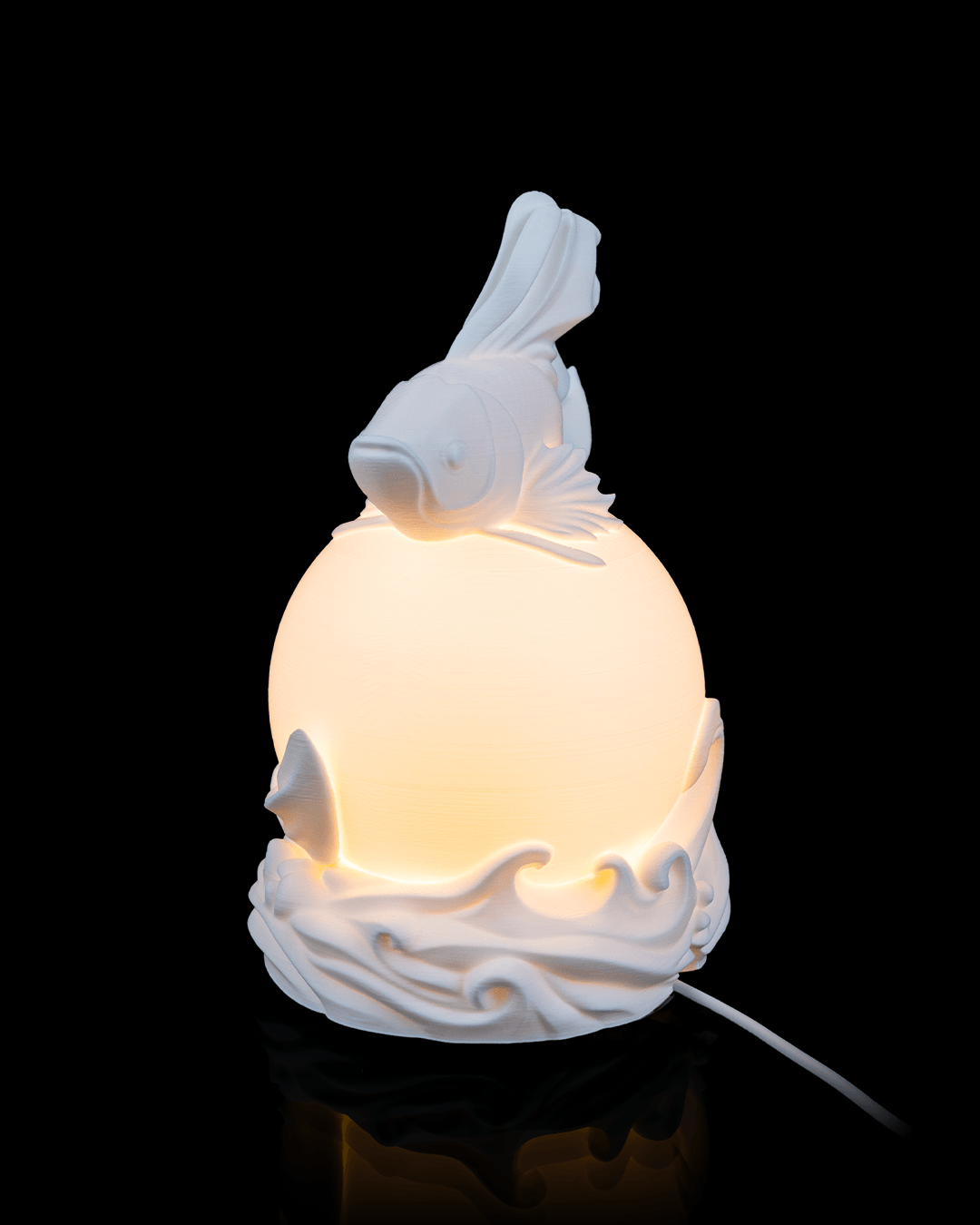 White ceramic lamp with fish design on a black background