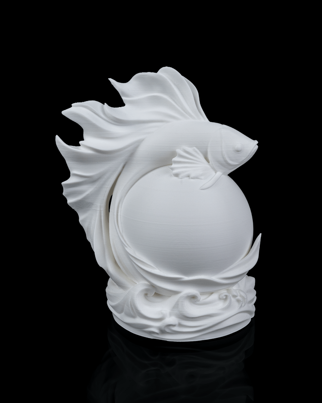 White ceramic sculpture of a fish with a ball on a black background