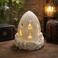 White 3D printed Dragon Egg Fairy Lamp glowing on a fantasy-themed wooden table.