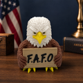 A small eagle figurine with a white head, brown body, yellow beak and talons, holding a sign that reads 'F.A.