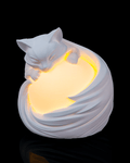 White ceramic cat-shaped night light emitting a warm glow on a black background