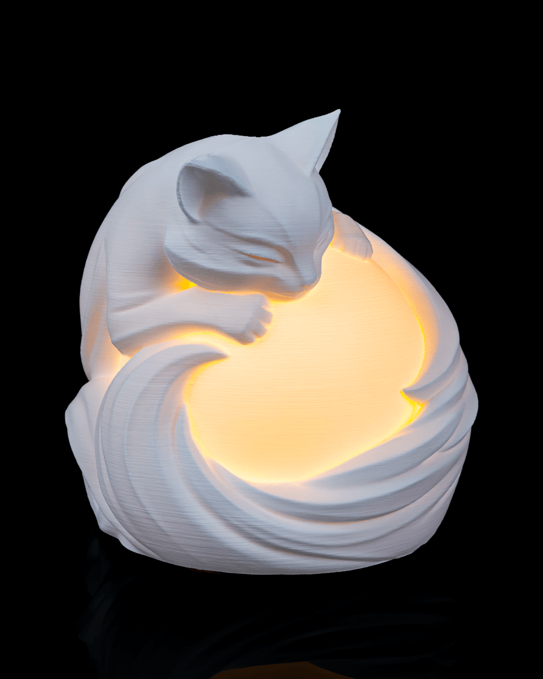 White ceramic cat-shaped night light emitting a warm glow on a black background