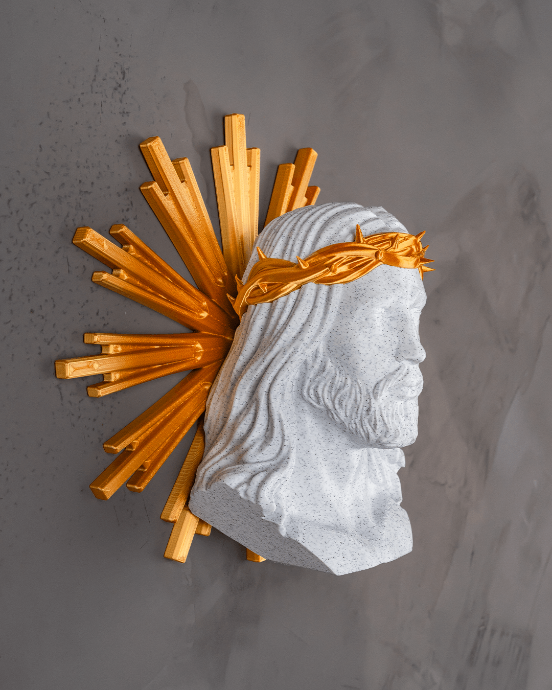 Decorative wall piece with stone head and gold sunburst on a gray background