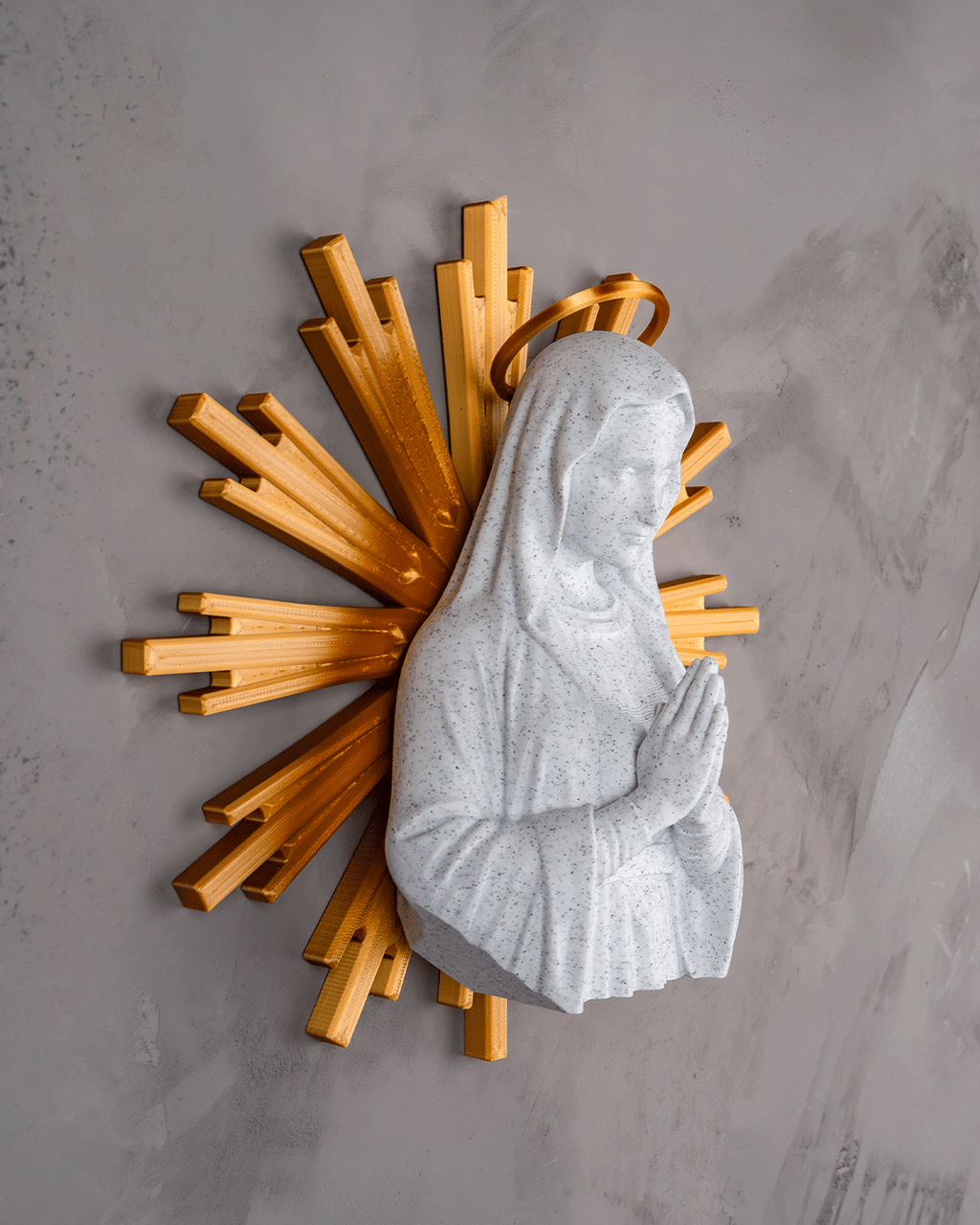 Statue of a praying figure with wooden sunburst design on a gray wall