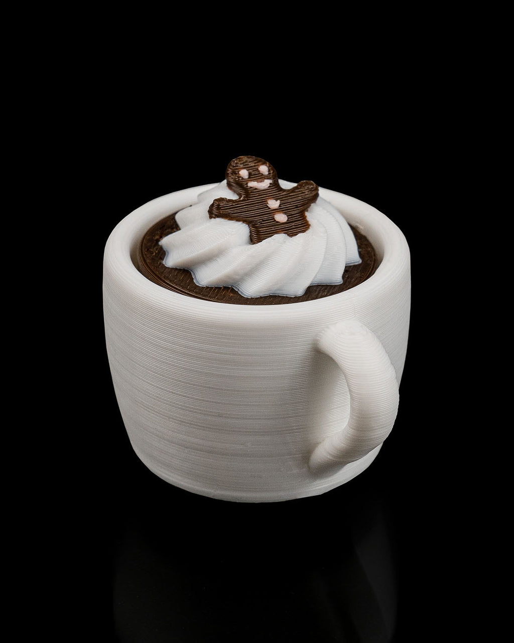 White mug with hot chocolate and whipped cream, topped with a gingerbread man on a black background