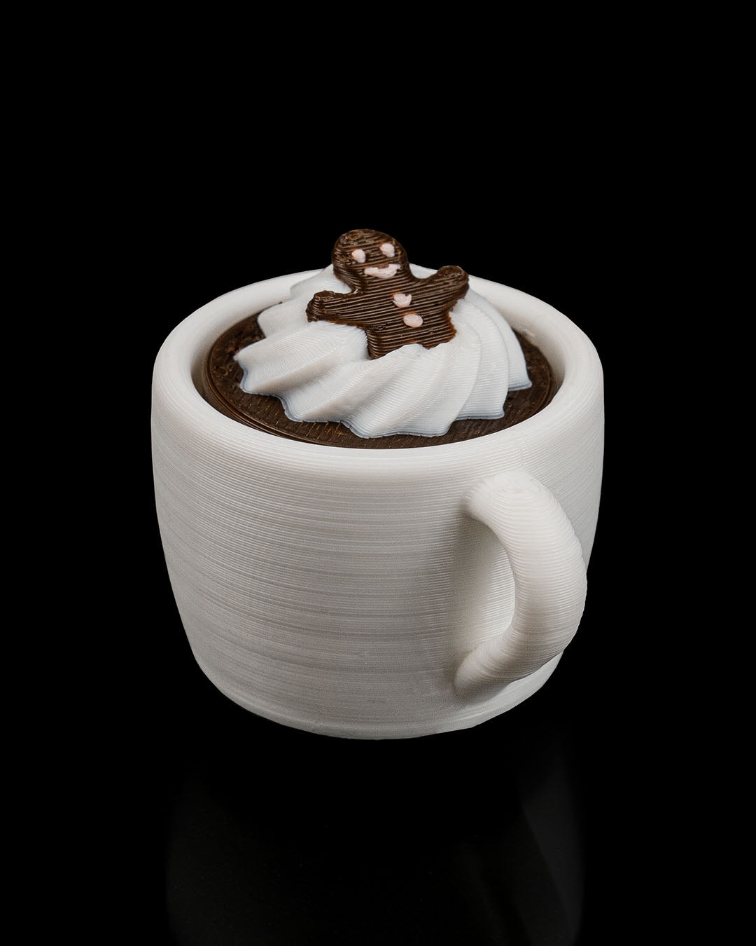 White mug with hot chocolate and whipped cream, topped with a gingerbread man on a black background
