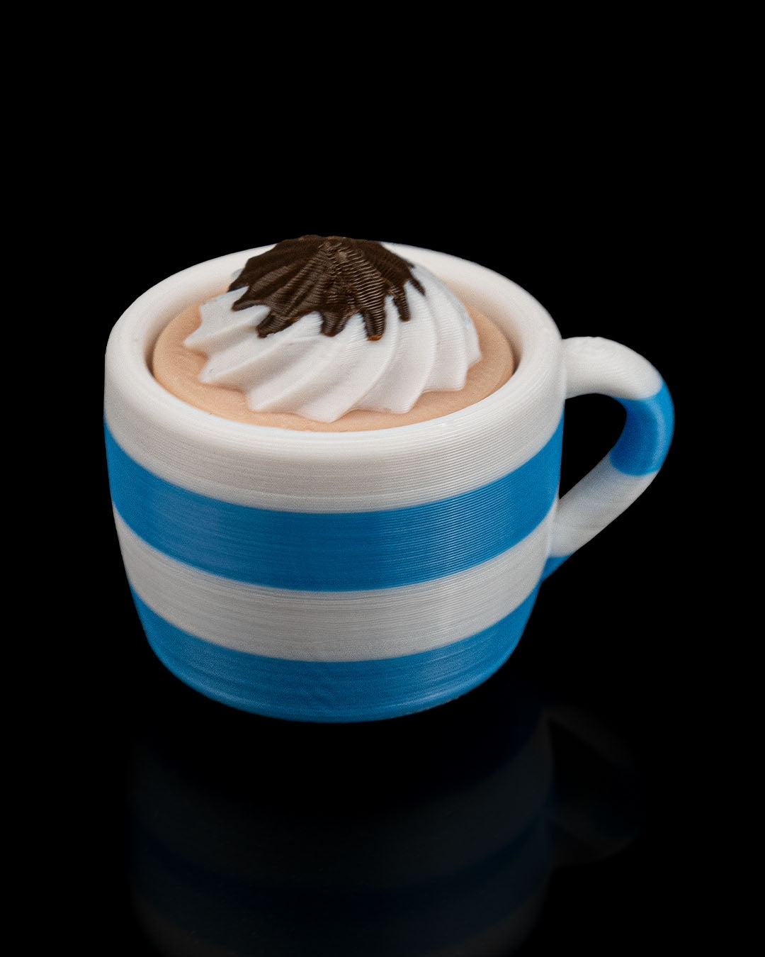 Blue and white striped mug with whipped cream and chocolate on a black background