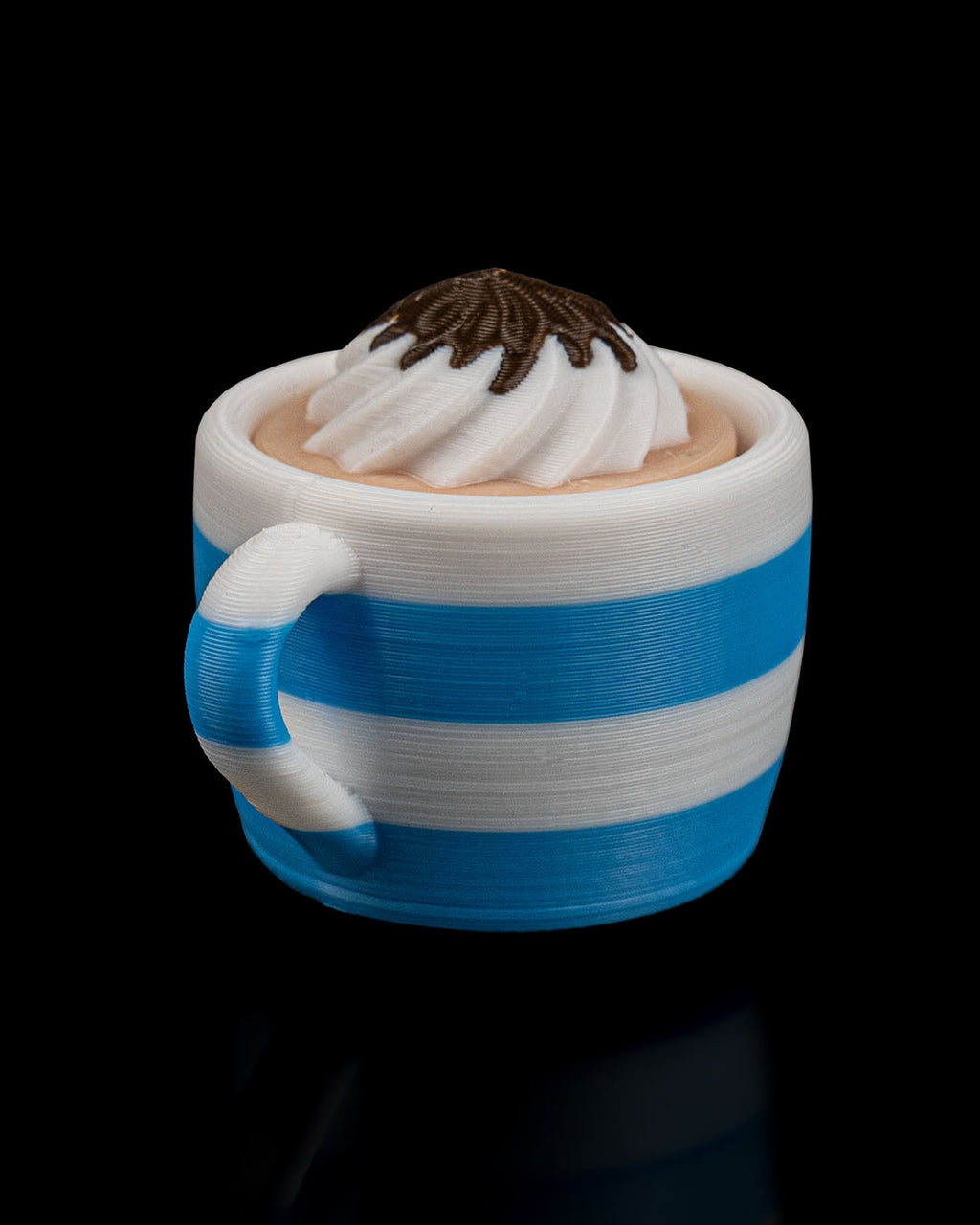 Blue and white striped mug with whipped cream and chocolate on a black background