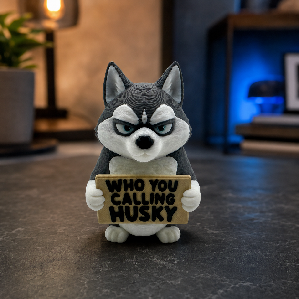 A small stylized husky figurine holding a sign that reads “WHO YOU CALLING HUSKY,” photographed on a dark tabletop with a softly blurred indoor background.