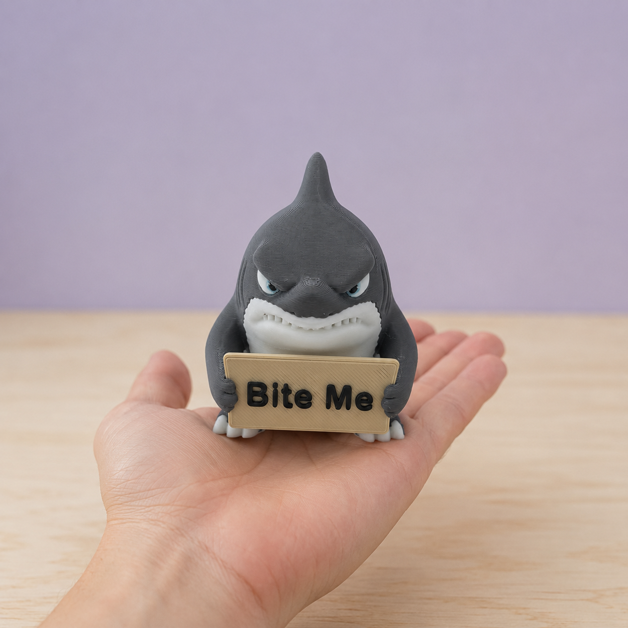 Small 3D-printed Bite Me shark figurine resting on an adult hand to demonstrate approximate scale.