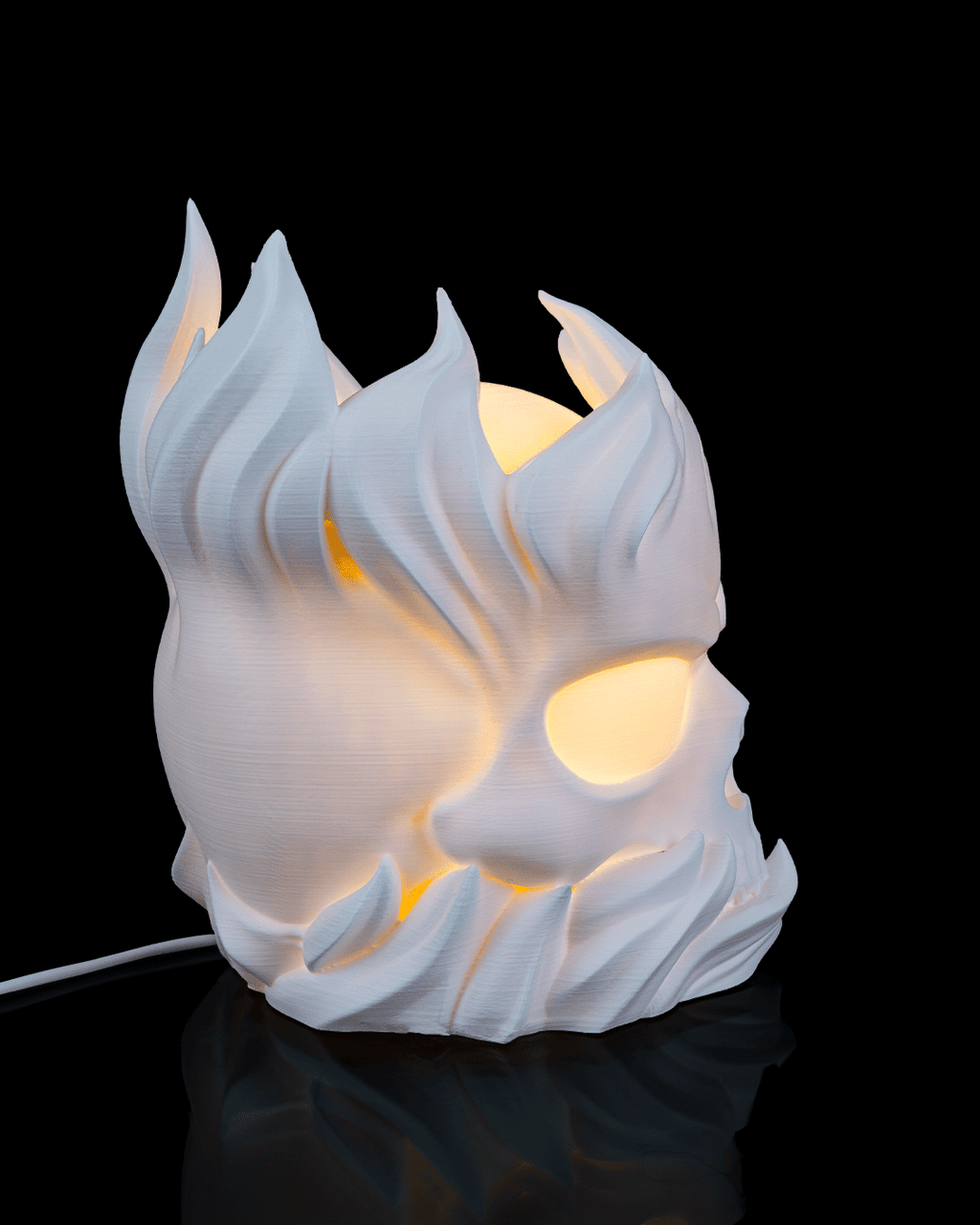 White ceramic lamp shaped like a stylized face with flame-like features on a black background