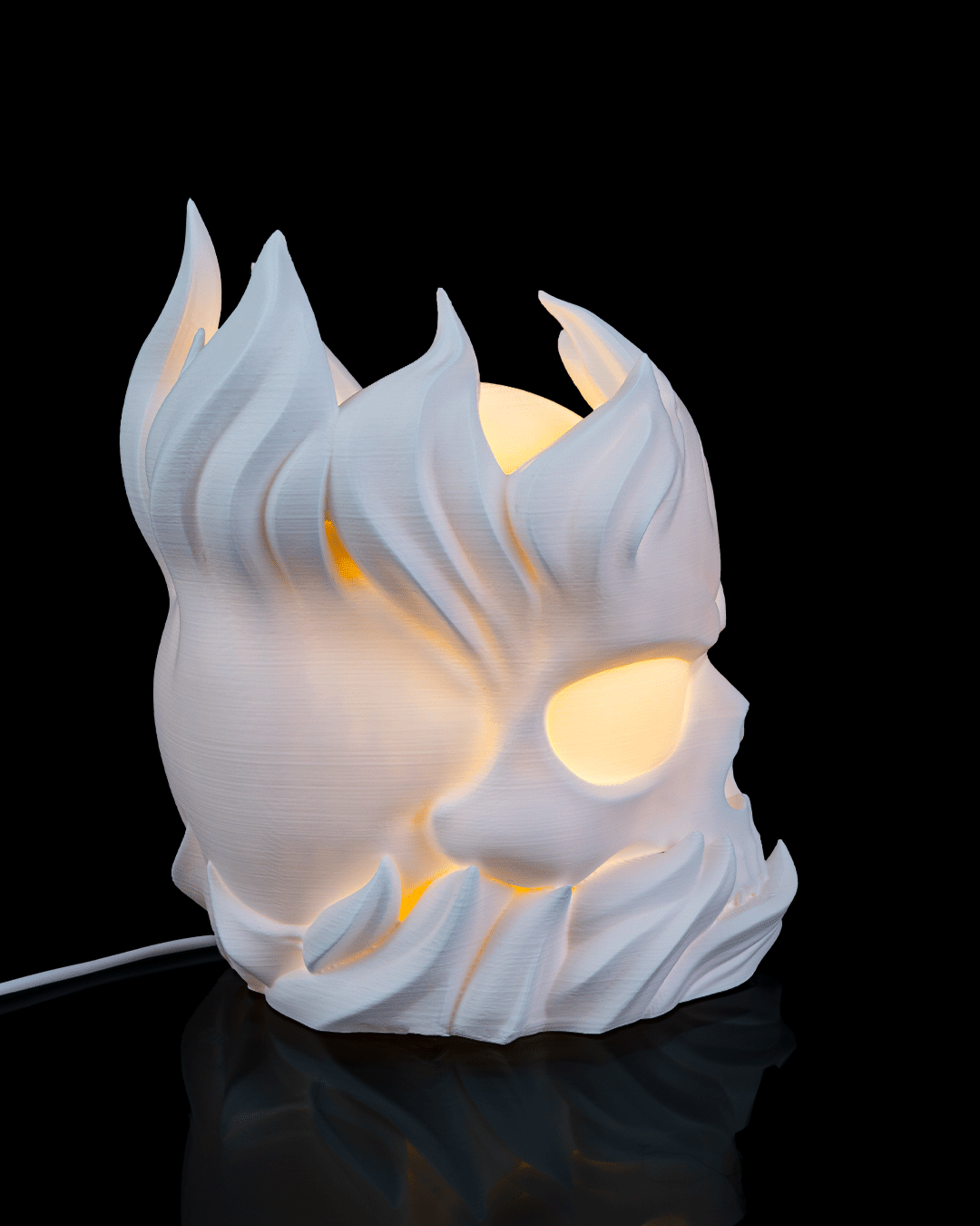 White ceramic lamp shaped like a stylized face with flame-like features on a black background