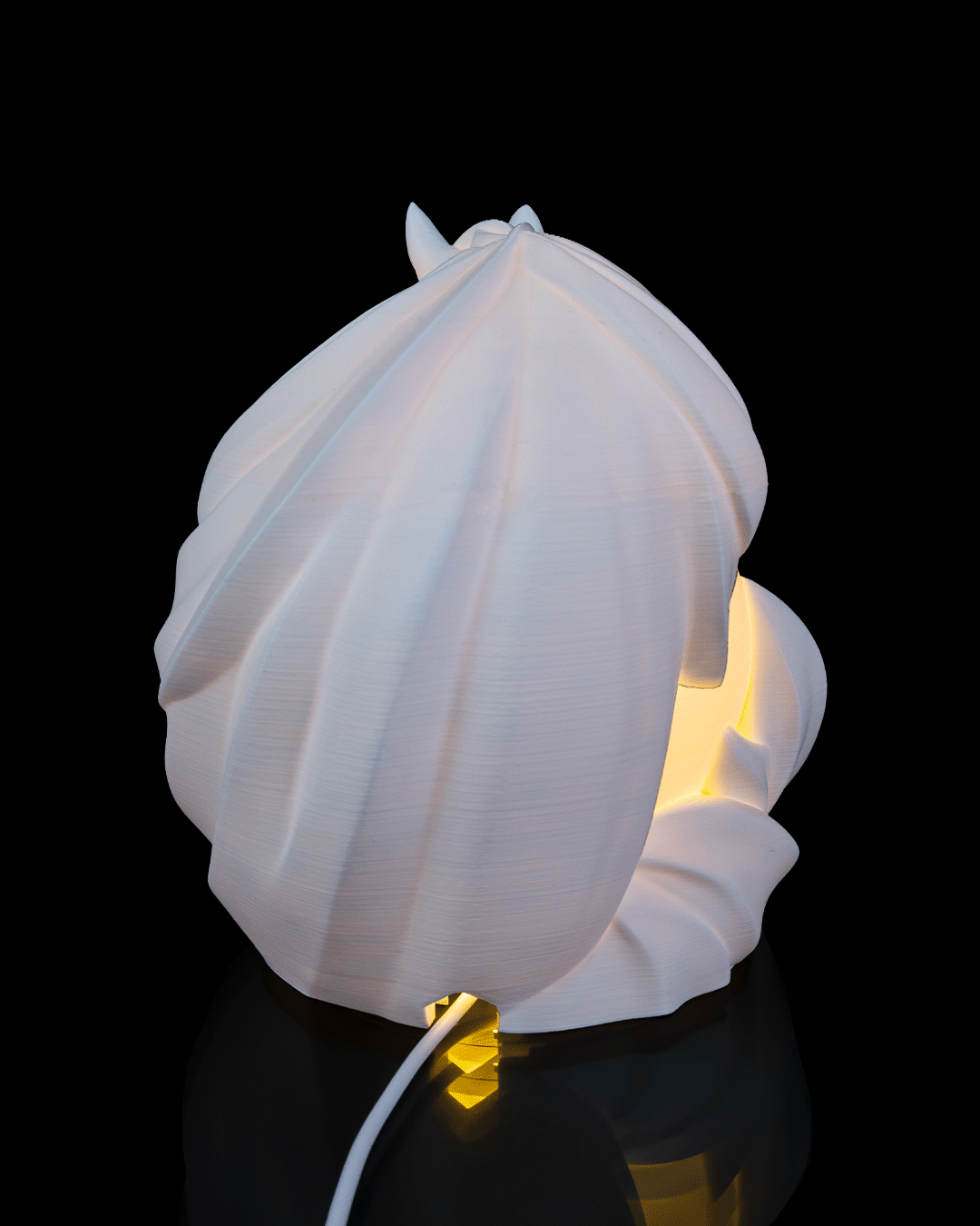 White shell-shaped lamp with a glowing interior on a black background