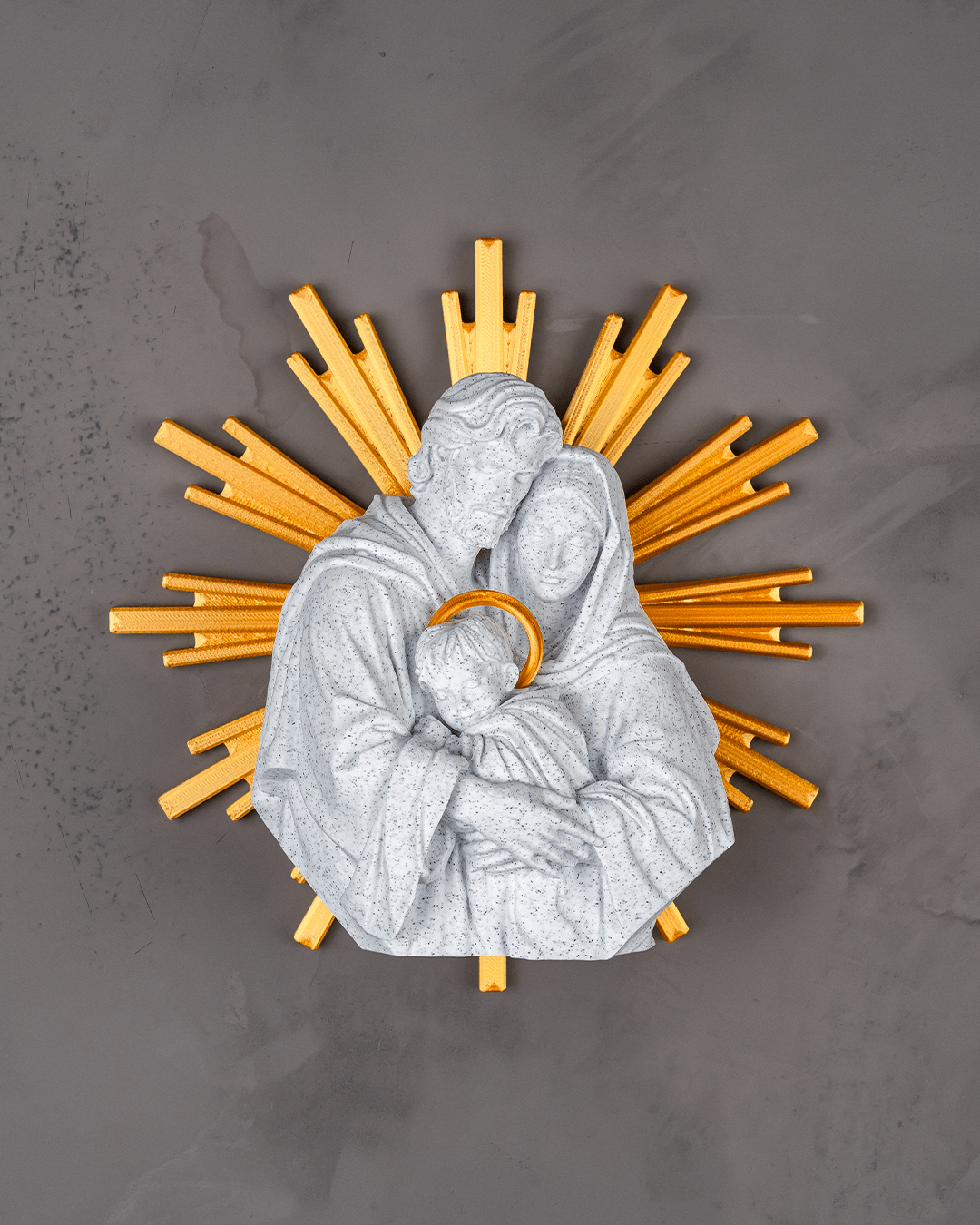 Decorative wall piece with a central figure holding a child, surrounded by yellow rays on a gray background